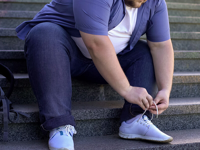 Obese man tying shoes